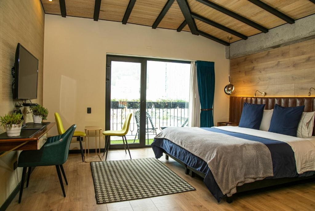 A wide view of a hotel room with a bed, desk, and sliding glass door.