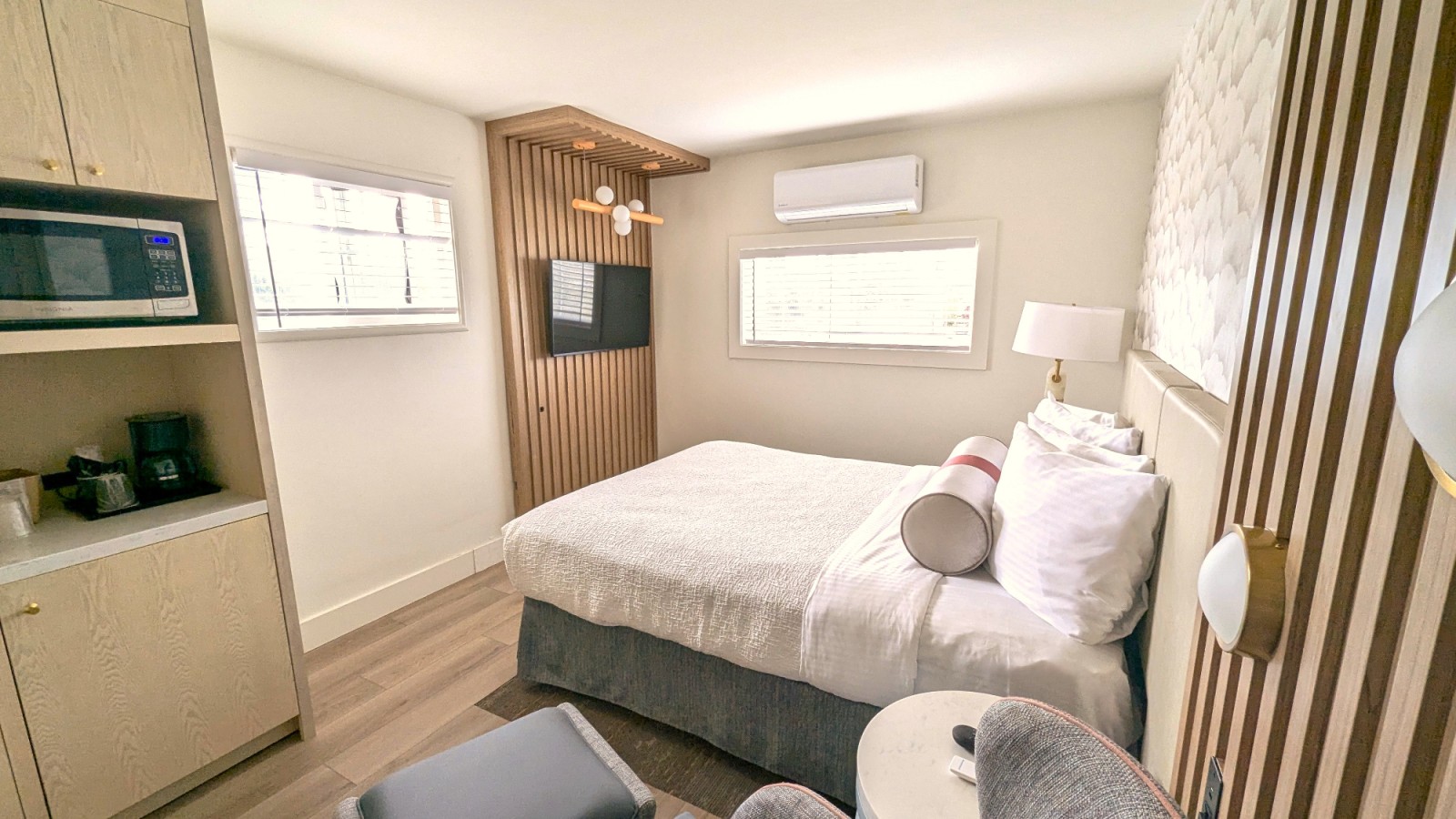 A hotel room with a bed, TV, microwave, and coffee maker.