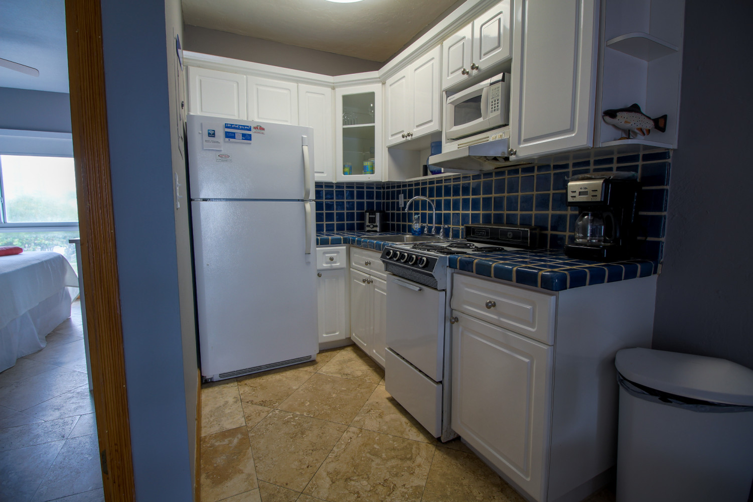 A kitchen with white cabinets, blue tile backsplash, and white appliances.