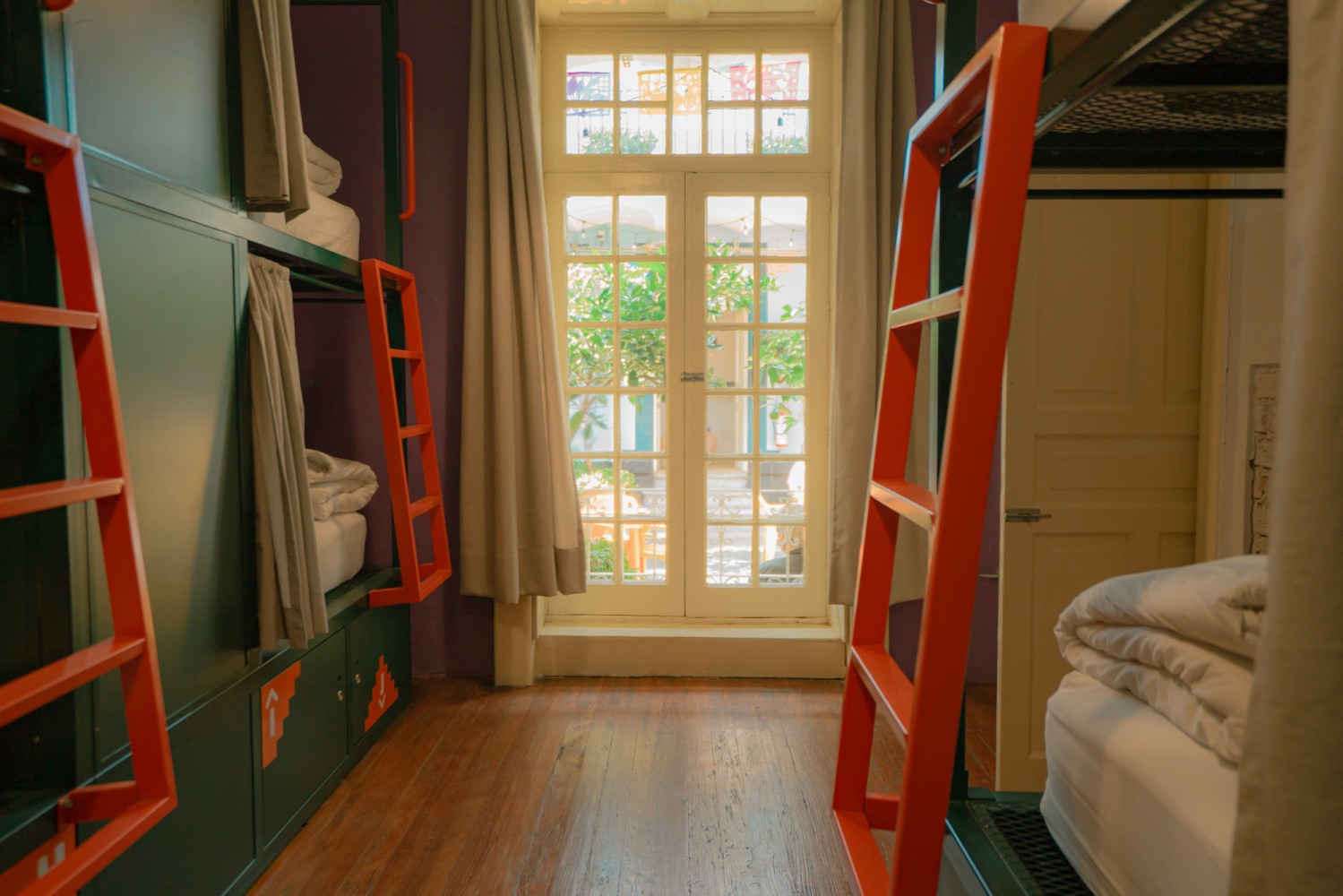 A room with bunk beds, a window, and a door.