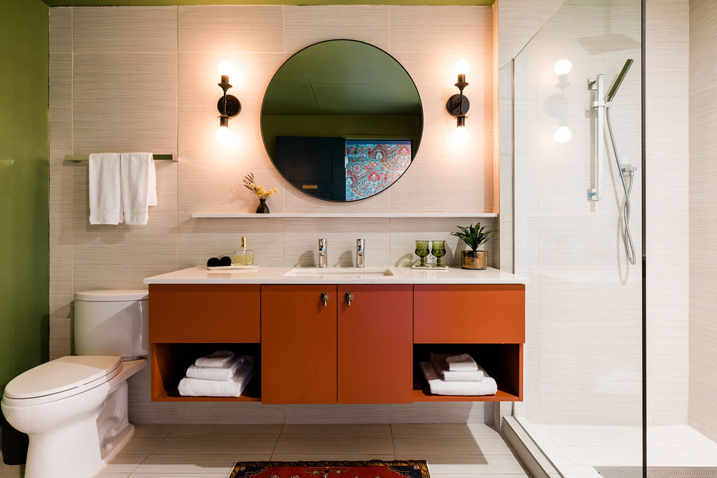 A modern bathroom with a double vanity, toilet, and glass-enclosed shower