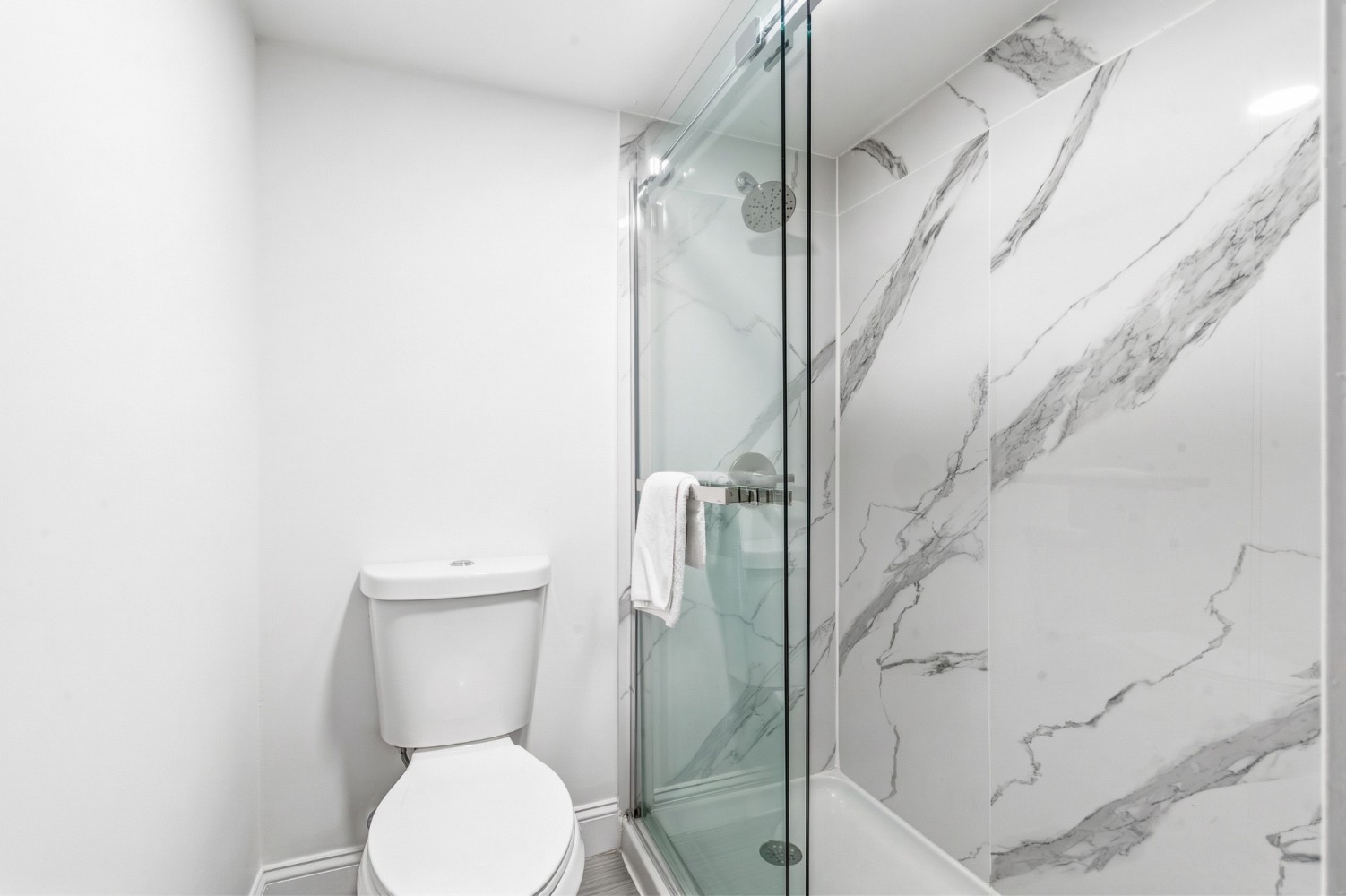 A bathroom with a toilet and a shower with marble walls