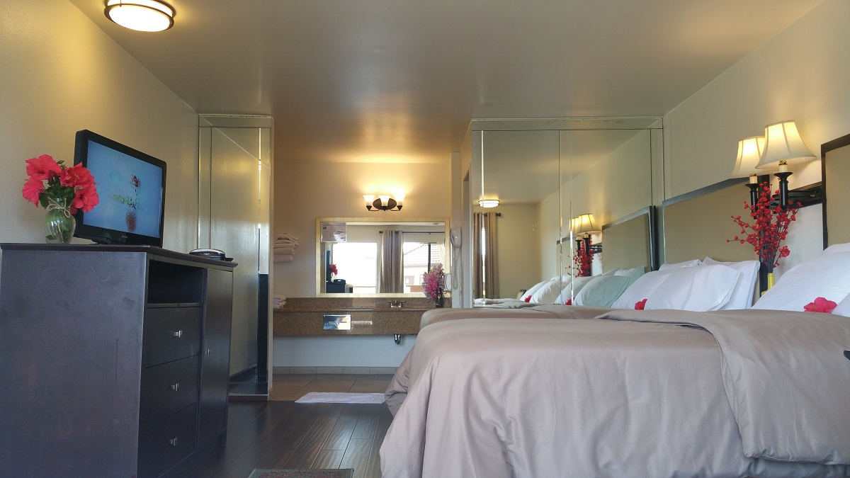 A hotel room with a double bed, TV, and mirror