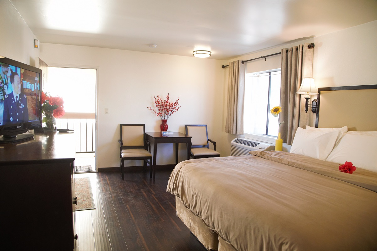 A hotel room with a bed, TV, table, chairs, and window