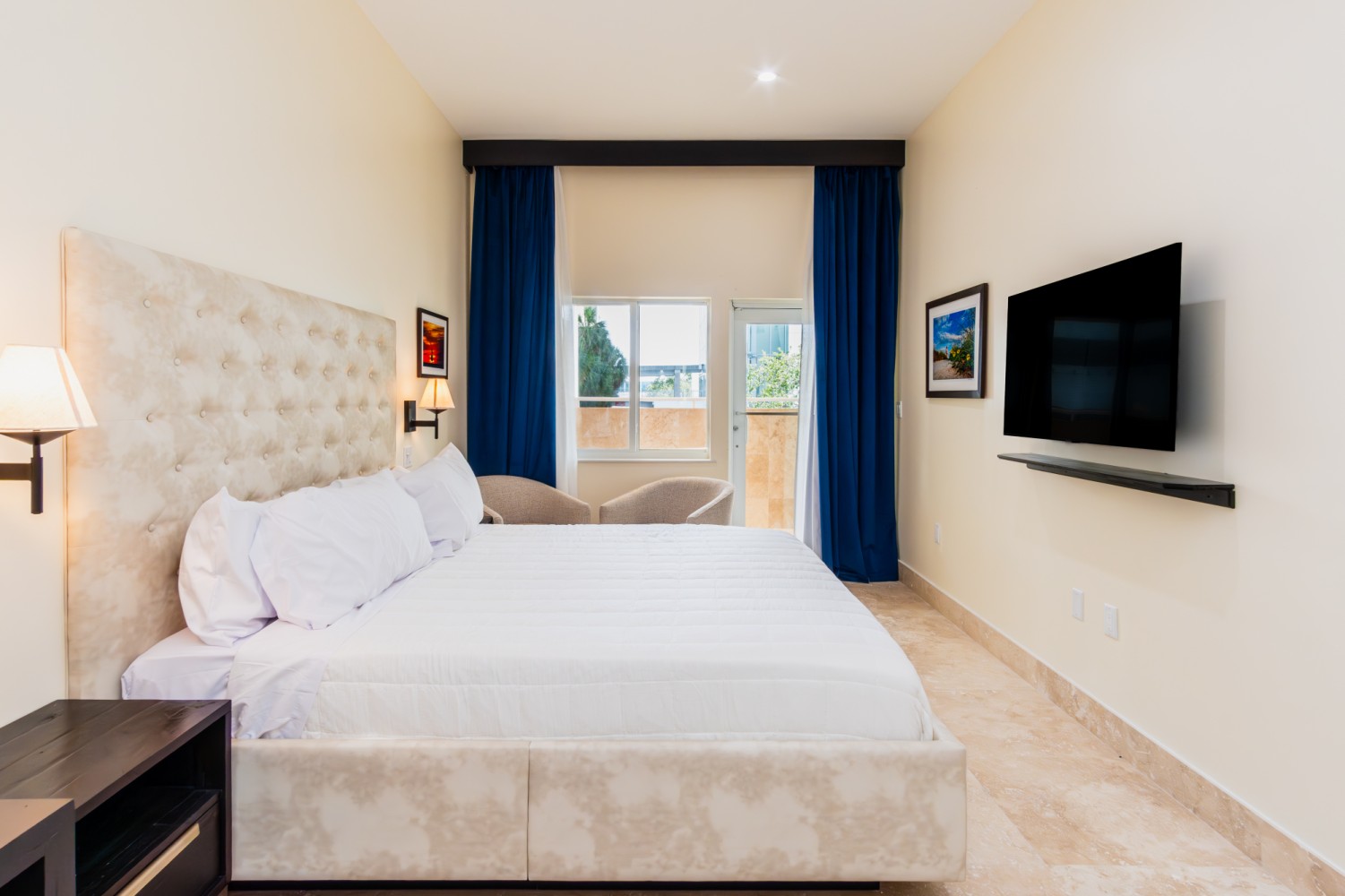 A hotel room with a large bed, TV, and balcony